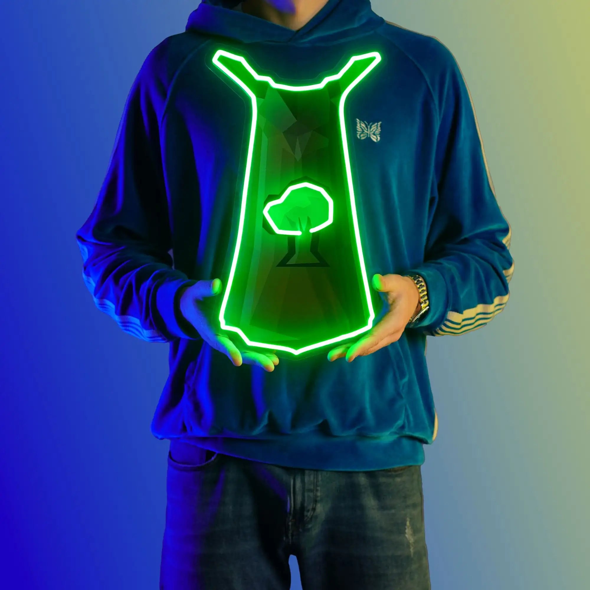 A person proudly displays the Runescape Woodcutting Skillcape LED neon sign, featuring the iconic Woodcutting Skillcape from the game. This LED neon sign symbolizes the dedication and perseverance of woodcutters in RuneScape. A symbol of hard work and mastery, it adds a touch of rustic charm to any gaming space.