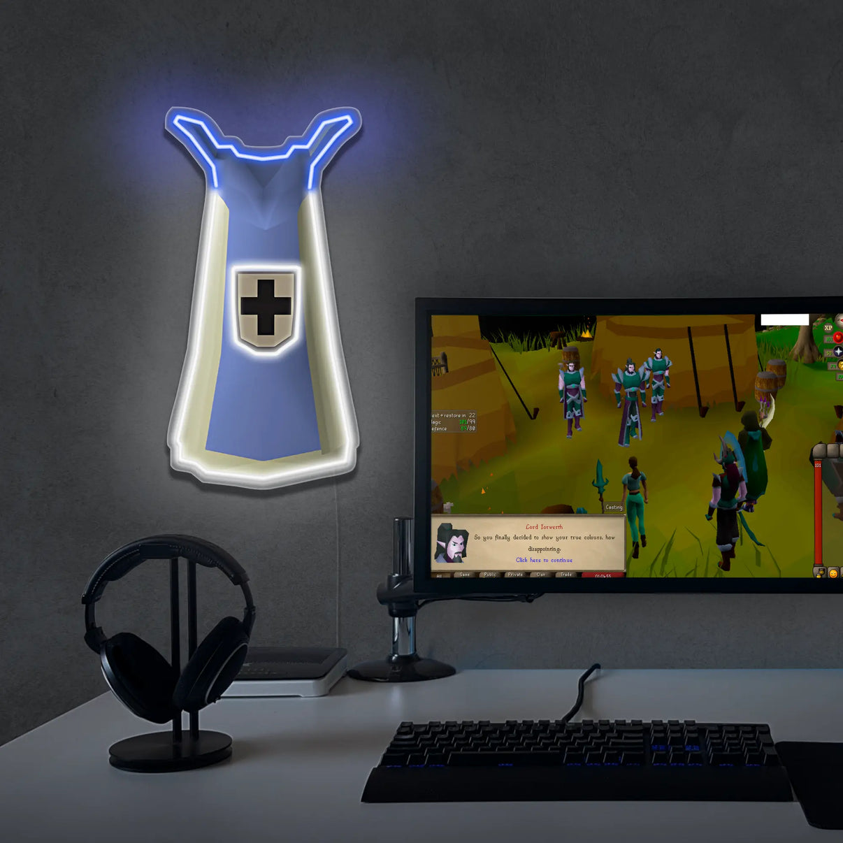 Gaming setup with a monitor displaying a game, keyboard, and decorative defence cape neon sign.