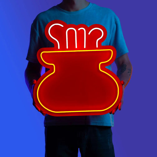 A person proudly holds the OSRS Cooking LED neon sign, showcasing the cooking pot symbol from Old School RuneScape. This LED neon sign celebrates the culinary achievements of RuneScape players, radiating a sense of pride and accomplishment. 