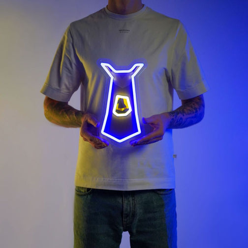 A person proudly displays the Runescape Magic Skillcape LED neon sign, featuring the iconic Magic Skillcape from the game. This LED neon sign represents mastery of the arcane arts in Old School RuneScape. A magical and prestigious addition to any gaming space.