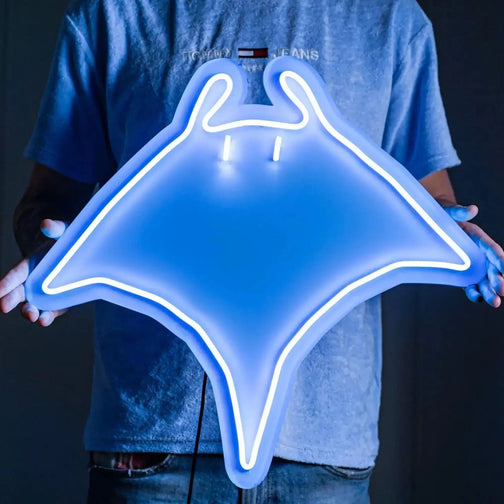 A person proudly displays the Runescape Manta Ray LED neon sign, featuring the iconic Manta Ray from the game. This LED neon sign represents the essential food source for adventurers in Old School RuneScape. A nostalgic and practical addition to any gaming space.
