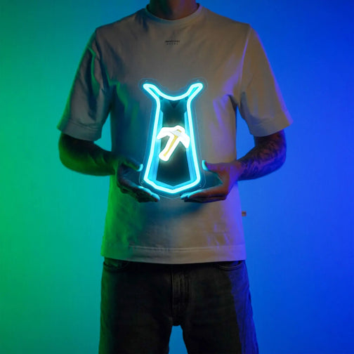 A person proudly displays the Runescape Mining Skillcape LED neon sign, featuring the iconic Mining Skillcape from the game. This LED neon sign represents mastery of the mining profession in Old School RuneScape. A symbol of hard work and dedication, it adds a touch of authenticity to any gaming space.