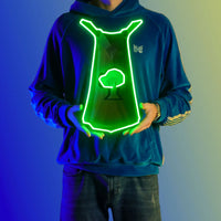 A person proudly displays the Runescape Woodcutting Skillcape LED neon sign, featuring the iconic Woodcutting Skillcape from the game. This LED neon sign symbolizes the dedication and perseverance of woodcutters in RuneScape. A symbol of hard work and mastery, it adds a touch of rustic charm to any gaming space.